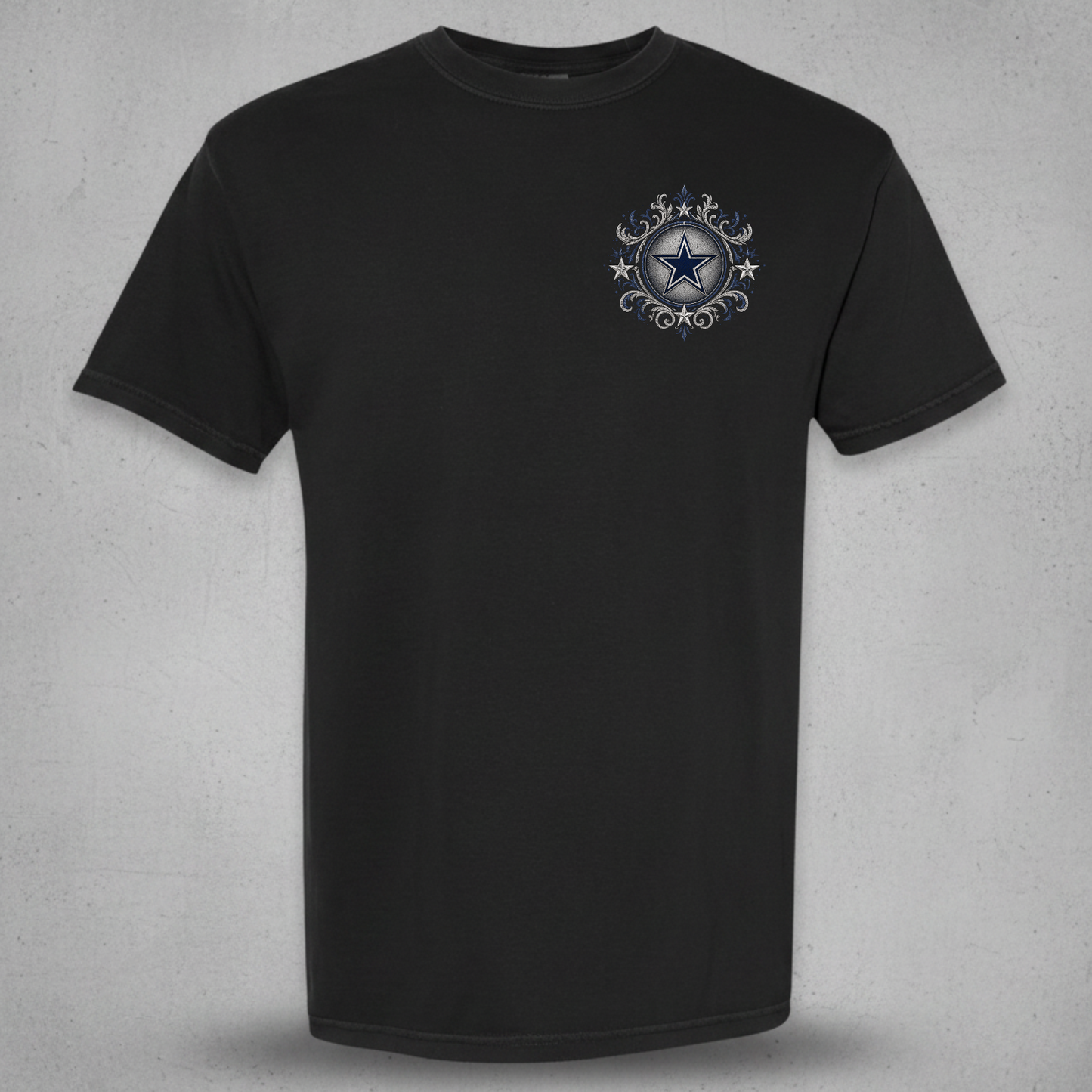 A black short-sleeve crewneck t-shirt with a small circular graphic on the left chest featuring a blue star and silver decorative elements, displayed against a textured gray background.