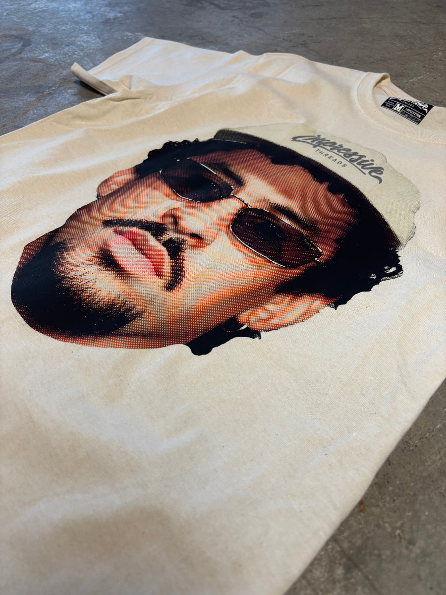 White t-shirt with a graphic of a bad bunny wearing sunglasses and a cap on a concrete surface.