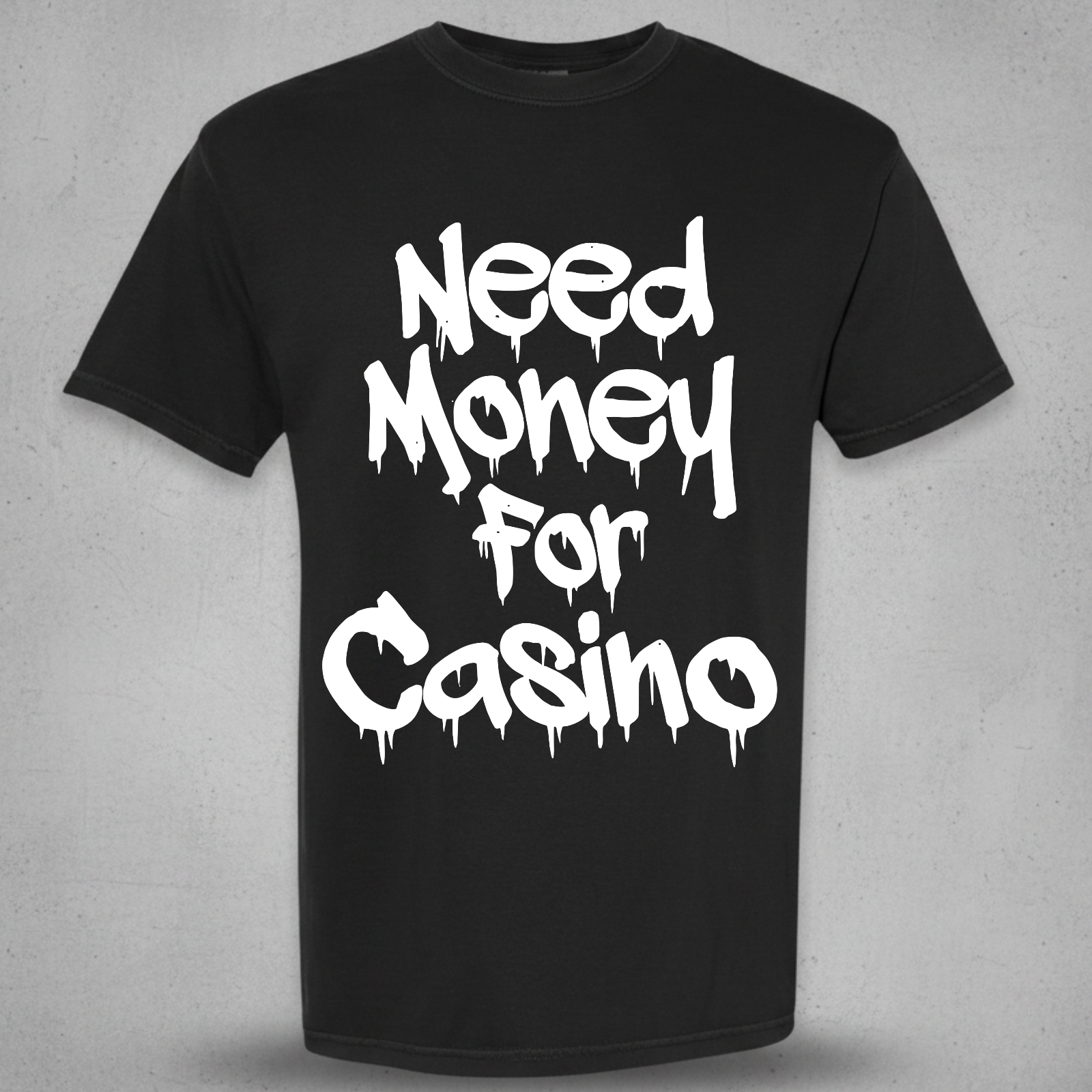 A black short-sleeve crewneck t-shirt with the phrase 'Need Money For Casino' printed in a white dripping graffiti-style font on the front, displayed against a textured gray background.
