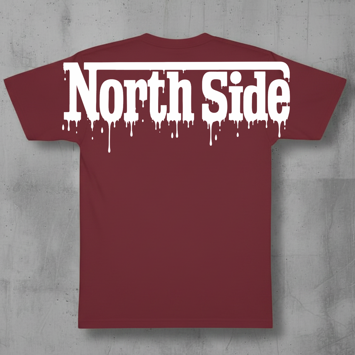 A maroon short-sleeve t-shirt with a white 'North Side' text graphic in a dripping font, displayed against a textured gray concrete background.