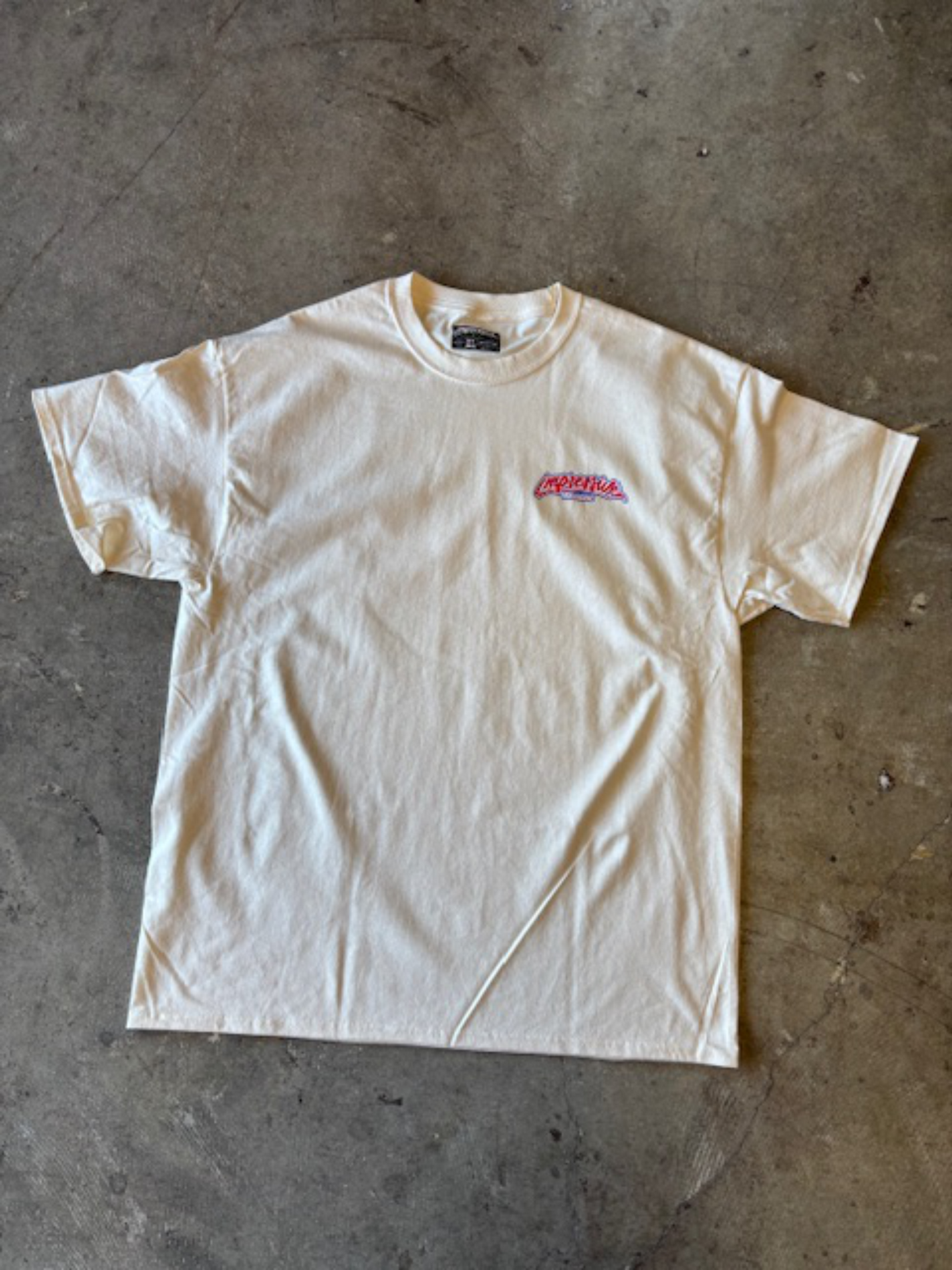 White t-shirt with a logo on a gray concrete floor